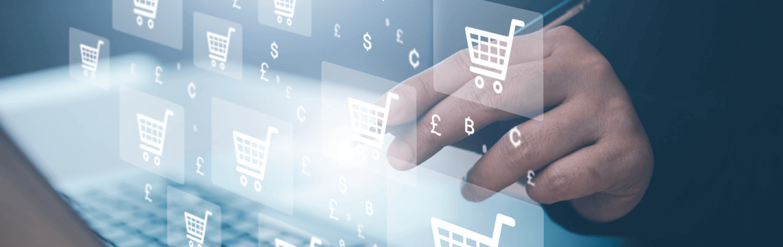 Hand holding pen over open laptop and reaching toward floating icons of digital shopping carts.