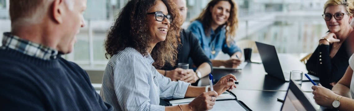 Several CFOs in a meeting, smiling and working together in partnership.