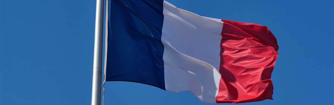 Flag of France blowing in the wind, with blue skies.
