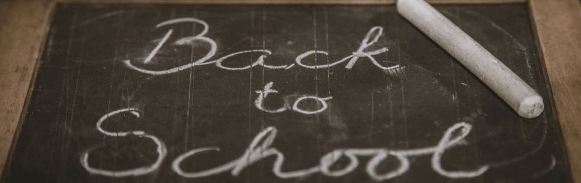 Back to school written on a small chalkboard, next to a piece of white chalk.